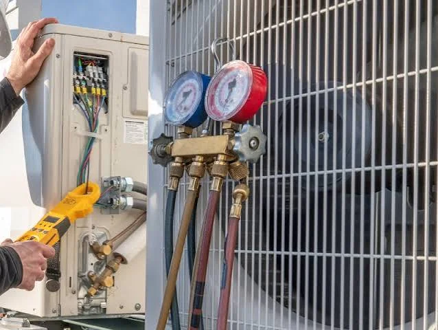 HVAC technician checking electrical connections and gauges during AC installation service