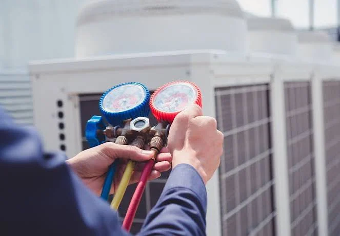 HVAC technician using manifold gauges to diagnose an outdoor cooling system
