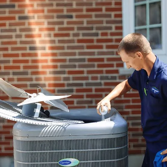 HVAC technician checking the fan assembly on an outdoor heat pump